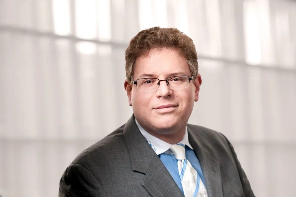 Marc Jonas Block, attorney at Ishimbayev Law Firm, in a grey suit and glasses